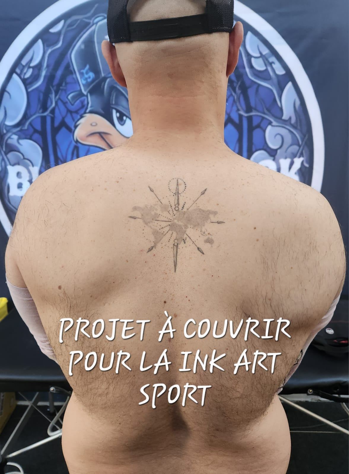Dos d'un client avant le recouvrement : un ancien tatouage de boussole sur fond de mappemonde, à couvrir pour la convention Ink Art Sport