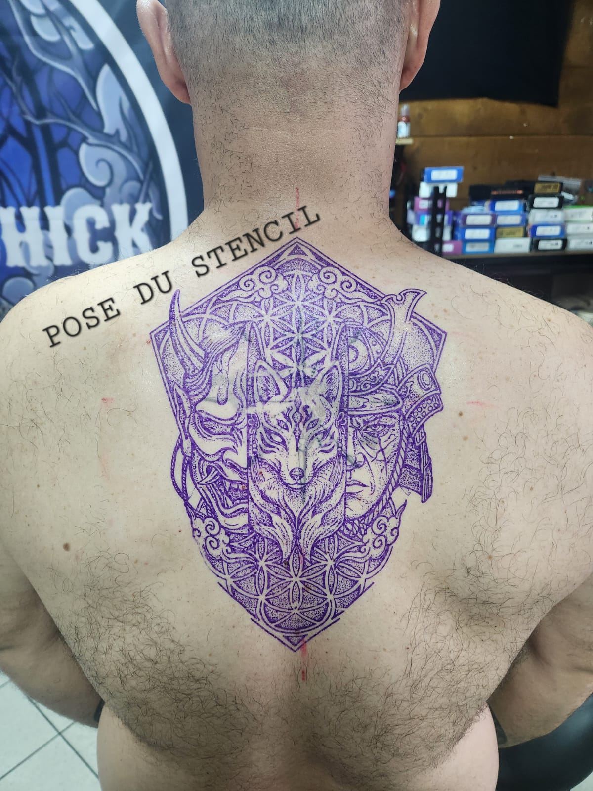 Stencil violet posé sur le dos : masque Hannya, masque de renard kitsune et samouraï sur un fond de fleur de vie
